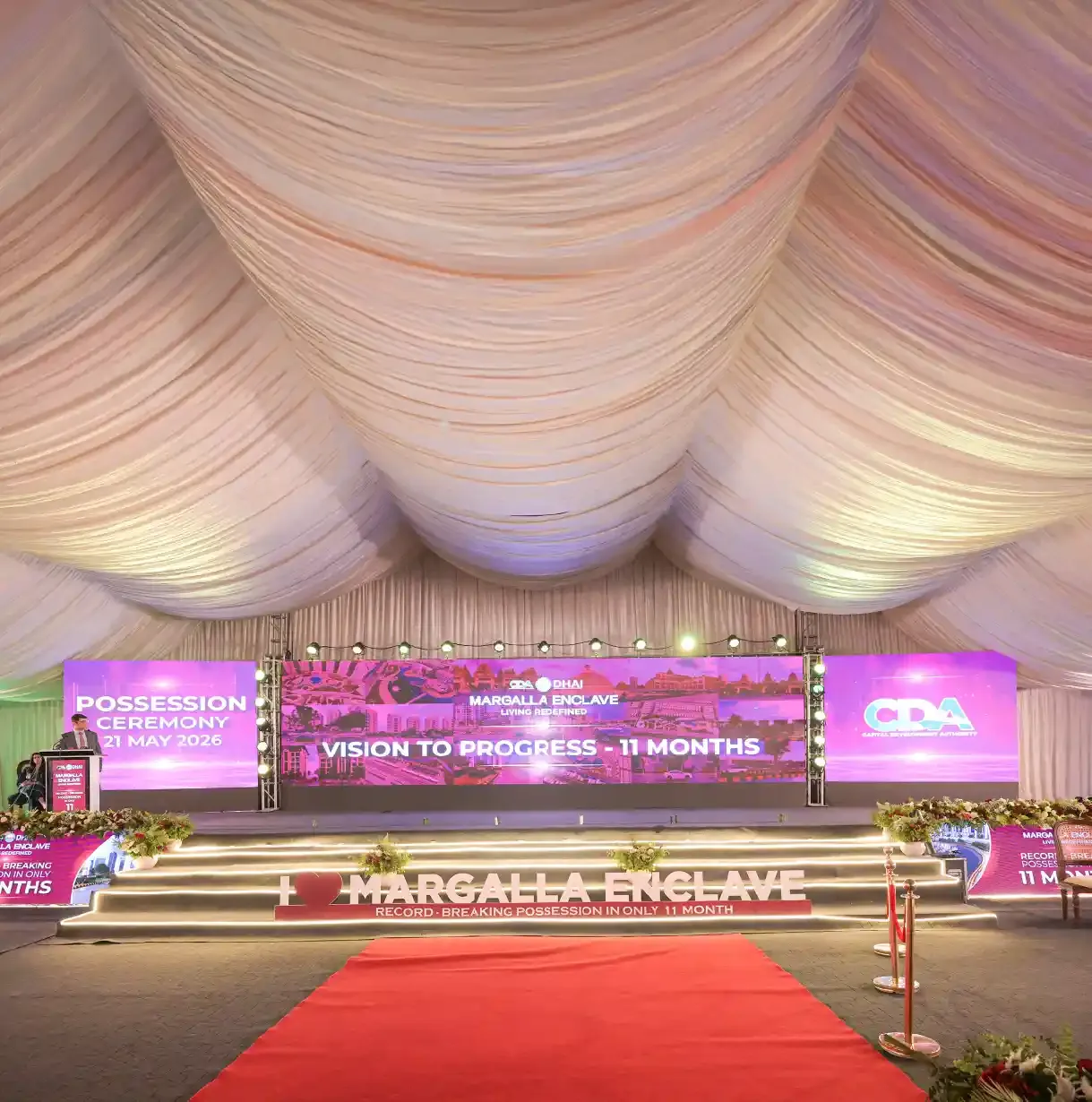 DHA Margalla Enclave possession ceremony, 21 May 2026 — CDA-DHA stage with 'Vision to Progress — 11 Months' and 'record-breaking possession in only 11 months' branding